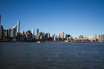 Obraz premium Buildings and bridge over river with blue sky, New York