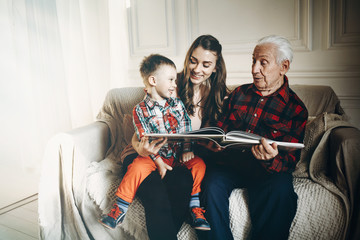Grandfather and grandson watch family album - obrazy, fototapety, plakaty