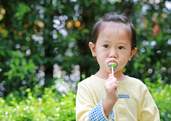 child girl enjoy eating lollipop candy in the park.