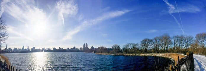 Lake at Central Park and buildings in Manhattan under the sun in panorama