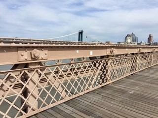 Wooden walkway and fence at Brooklyn bridge and Manhattan bridge with cloudy sky