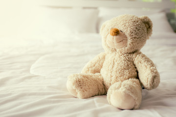Teddy bear with depression sitting on the bed, vintage color tone.