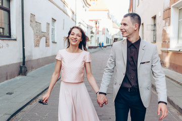 Stylish young couple in love walking on the street at sunset