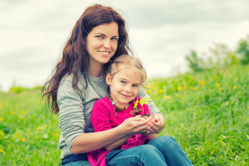 Fototapeta na wymiar Mother and daughter holding little green plant in hands. Ecology concept