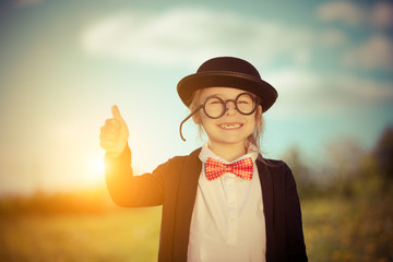 Funny little girl in bow tie and bowler hat showing thumb up. Retro stile.