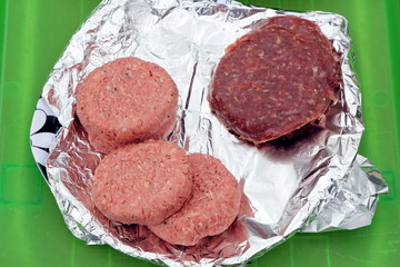 Two types of burger, traditional beefburgers and unusual zebra burgers, on tin foil waiting to be...