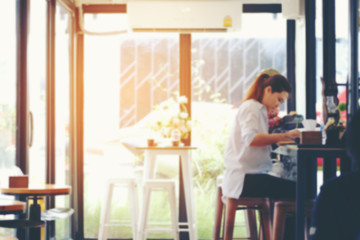 Abstract blur image of coffee shop interior and woman sitting while relaxing in cafe during free...