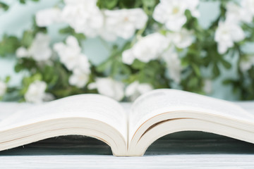 Open hardback book on wooden table and natural background. Back to school. Copy space for ad text.