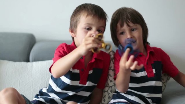 Little children, boy brothers, playing with colorful fidget spinner toys