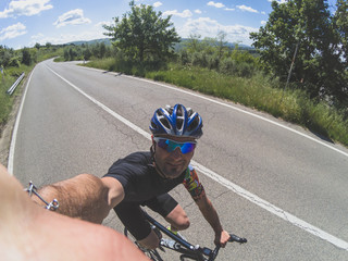 Young adult athlete takes a selfie while riding a racing bicycle on spring