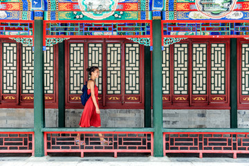 Young backpacker woman walking through old traditional long corridor at chinese temple, china...