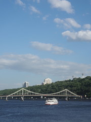 A white pleasure boat with passengers aboard sailed along the center of the river in Kiev
