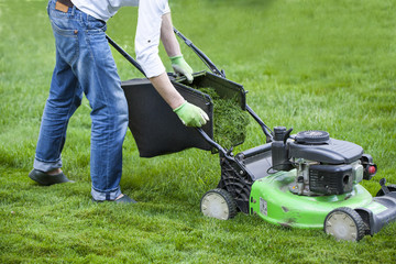 the man mowing lawn in the backyard of his house. Lawn mowing. Green grass is mowed lawn mower
