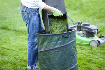 the man mowing lawn in the backyard of his house. Lawn mowing. Green grass is mowed lawn mower