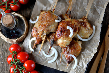 Delicious chicken kebab on wooden skewers on the old wooden background.