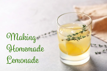 Glass of fresh lemonade on light background