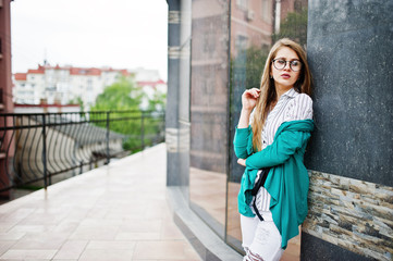 Fototapeta premium Trendy girl at glasses and ripped jeans against house on street.
