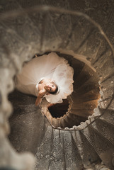 Beautiful bride in magnificent dress stands alone on stairs