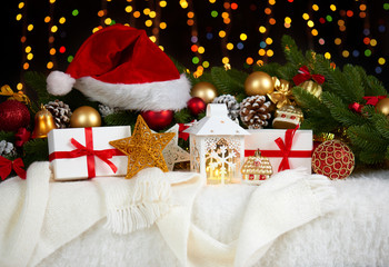 christmas decoration on white fur with fir tree branch closeup, gifts, xmas ball, cone and other object on dark background with lights, winter holiday concept