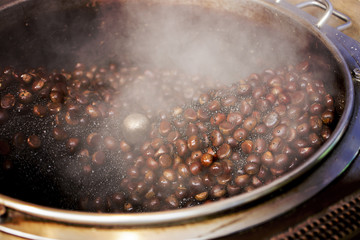 Roasted chestnuts in a hot pan, a step in roasting chestnut seeds with hot pebbles. selective focus.