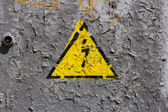The sign of electrical hazard on a gray coarse metaic painted surface