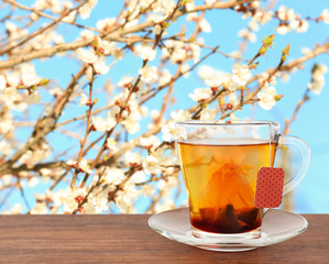 Glass cup with tea bag on wooden table over white background