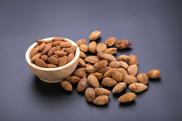 Almonds in wooden bowl on a black background