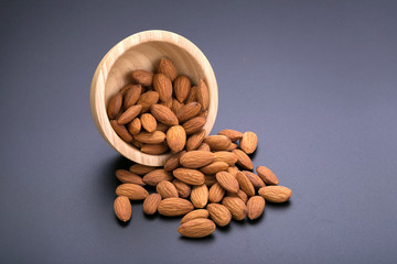 Almonds in wooden bowl on a black background