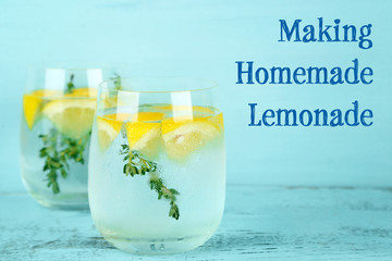 Tasty cool beverage with lemon and thyme, on wooden background