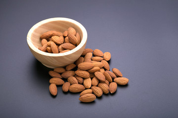 Almonds in wooden bowl on a black background