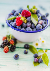 Fresh berries in bowl on wooden background.