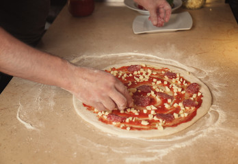 Cook preparing tasty pizza on kitchen table