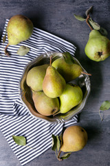 Heap of fresh pears in metal bowl on grey table, top view