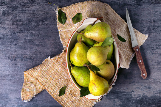 Heap of fresh pears in dish on grey table, top view