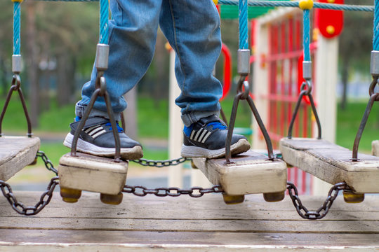 The legs of the child on a wooden bridge. Playground