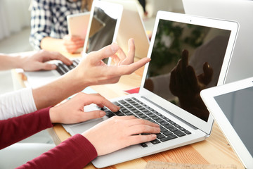 Young people with gadgets sitting at table, closeup