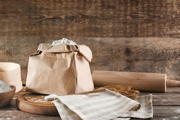 Fototapeta na wymiar Paper bag of wheat flour on wooden background