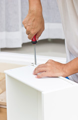 Asian Man's Hand Using Screw Driver Assembling Wooden Furniture