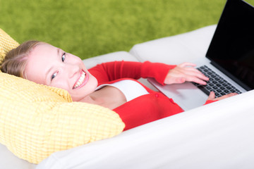 frau glücklich am notebook und entspannt auf couch