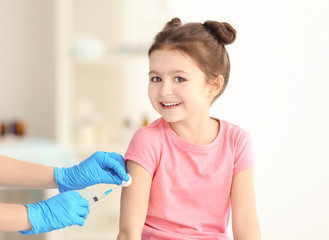Vaccination concept. Female doctor vaccinating cute little girl in clinic