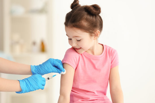 Vaccination concept. Female doctor vaccinating cute little girl in clinic