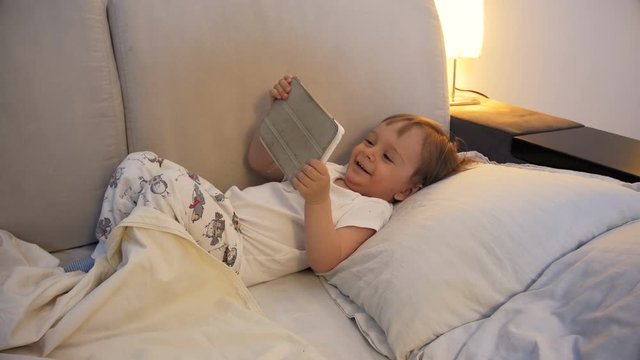 4k footage of cute small boy watching cartoons on tablet and laughing