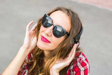 Young smiling woman relaxing and listening to music with headphones in the street