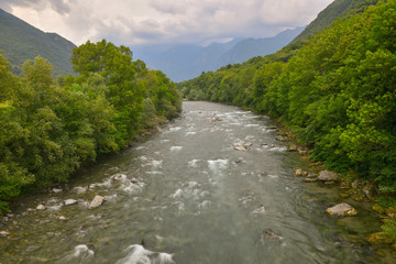 Panorama del fiume che scorre tra gli argini con alberi verdi