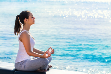 Fototapeta na wymiar Woman meditating next to sea.