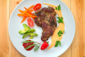Grilled pork steak and vegetables on the grill. Horizontal, rustic style. Wooden background. Close-up. Top view