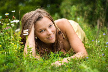 Naklejka na ściany i meble Beautiful woman enjoys nature in summer bloom. Perfect body. The girl has a beautiful face, bright eyes. Photo was taken in nature in summer solstice.