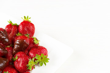 Strawberries dipped in delicious chocolate in white dish isolated on white background. Close up view.