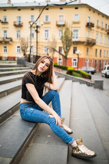 urban young woman sit on stairs with hood full body shot