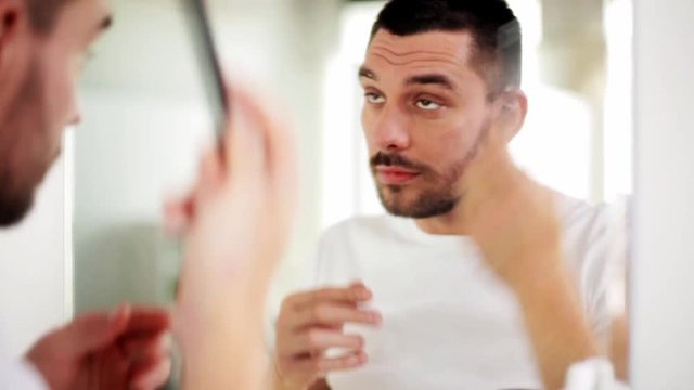happy man brushing hair with comb at bathroom